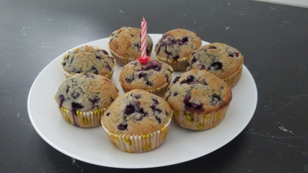 Ein Teller mit Muffins. In einem Muffin steckt eine Geburtstagskerze