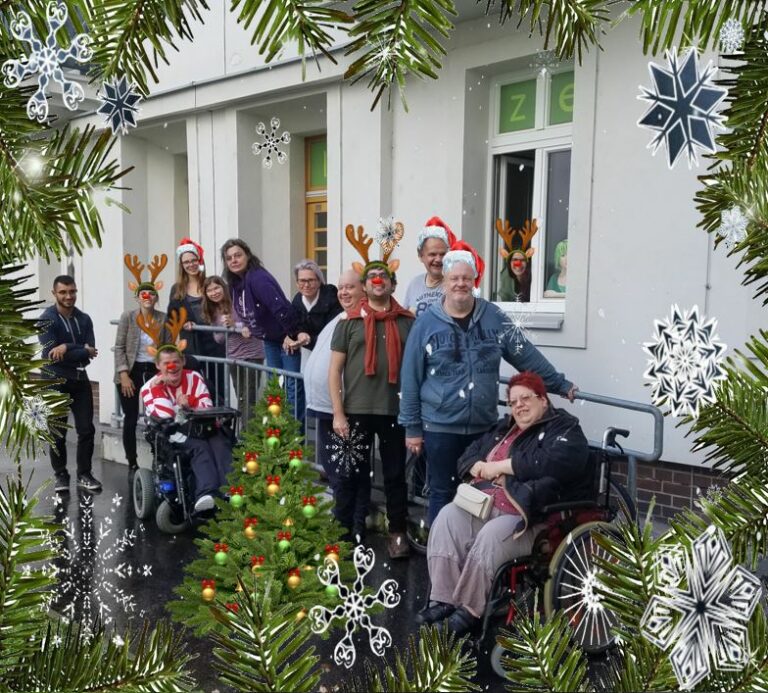 Teamfoto der Agentur Sonnenklar Drehscheibe Peer-Streitschlichtung. Die Personen stehen bzw. sitzen vor dem Büro. Manche Personen haben eine Weihnachtsmütze auf.