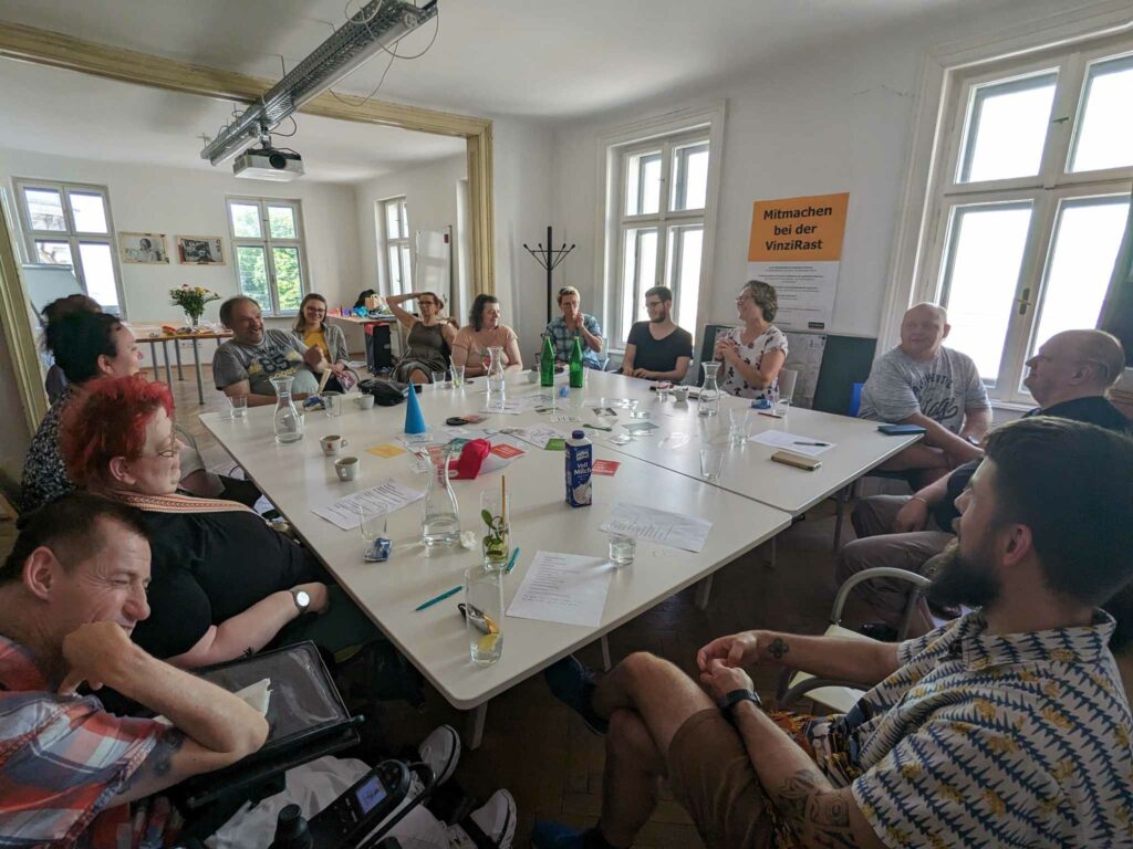 Das Team der Agentur Sonnenklar Drehscheibe Peer Streitschlichtung bei der Klausur. Alle sitzen um einen Eckigen Tisch auf dem viele Sachen liegen.