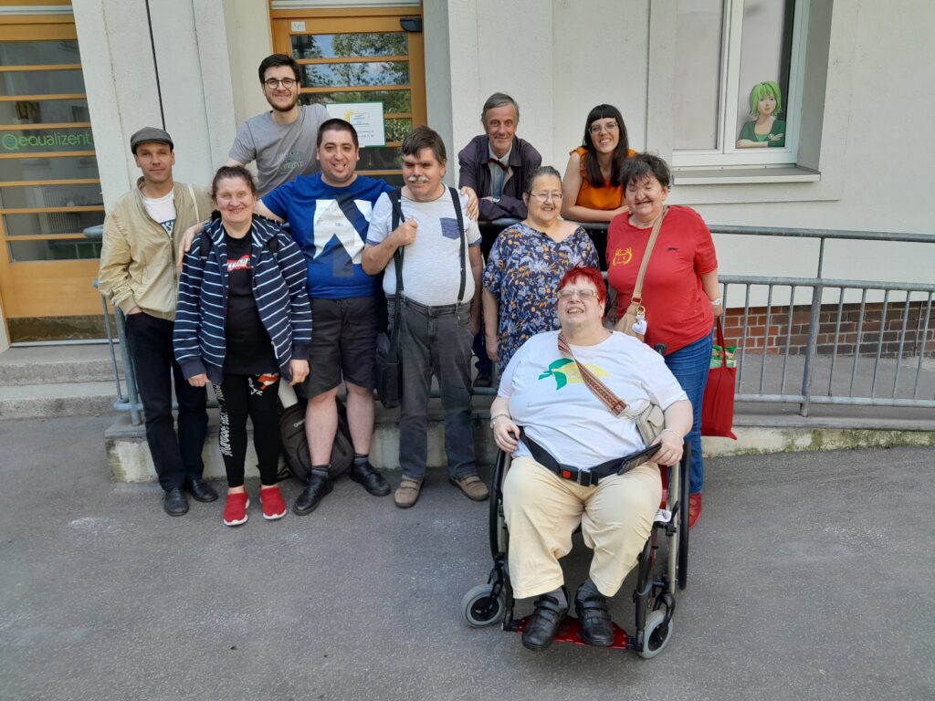 Eine Gruppe von Personen lacht nach einem Workshop in die Kamera. Sie stehen vor dem Büro der Agentur Sonnenklar.