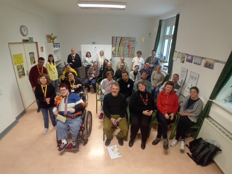 Gruppenfoto aller Teilnehmer*innen und Vortragenden vom Workshop. ungefähr 25 Personen sitzen oder stehen im Workshopraum von Sonnenklar und lachen in die Kamera.